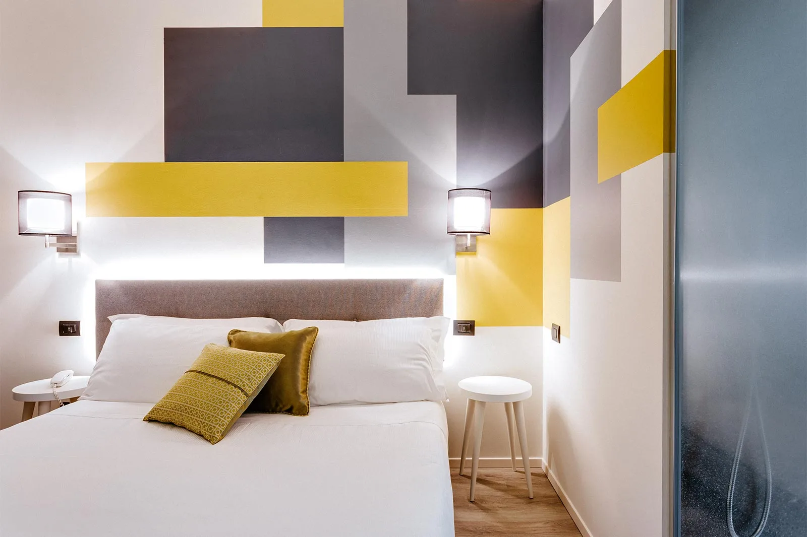 arredamento hotel geometrie camera giallo dettaglio comodini testata