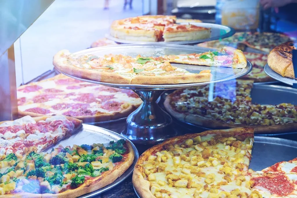 Pizze rotonde di gusti diversi tagliate in spicchi e conservate nella vetrina
